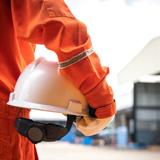 Worker in high visibility jumpsuit with a white hard hat.