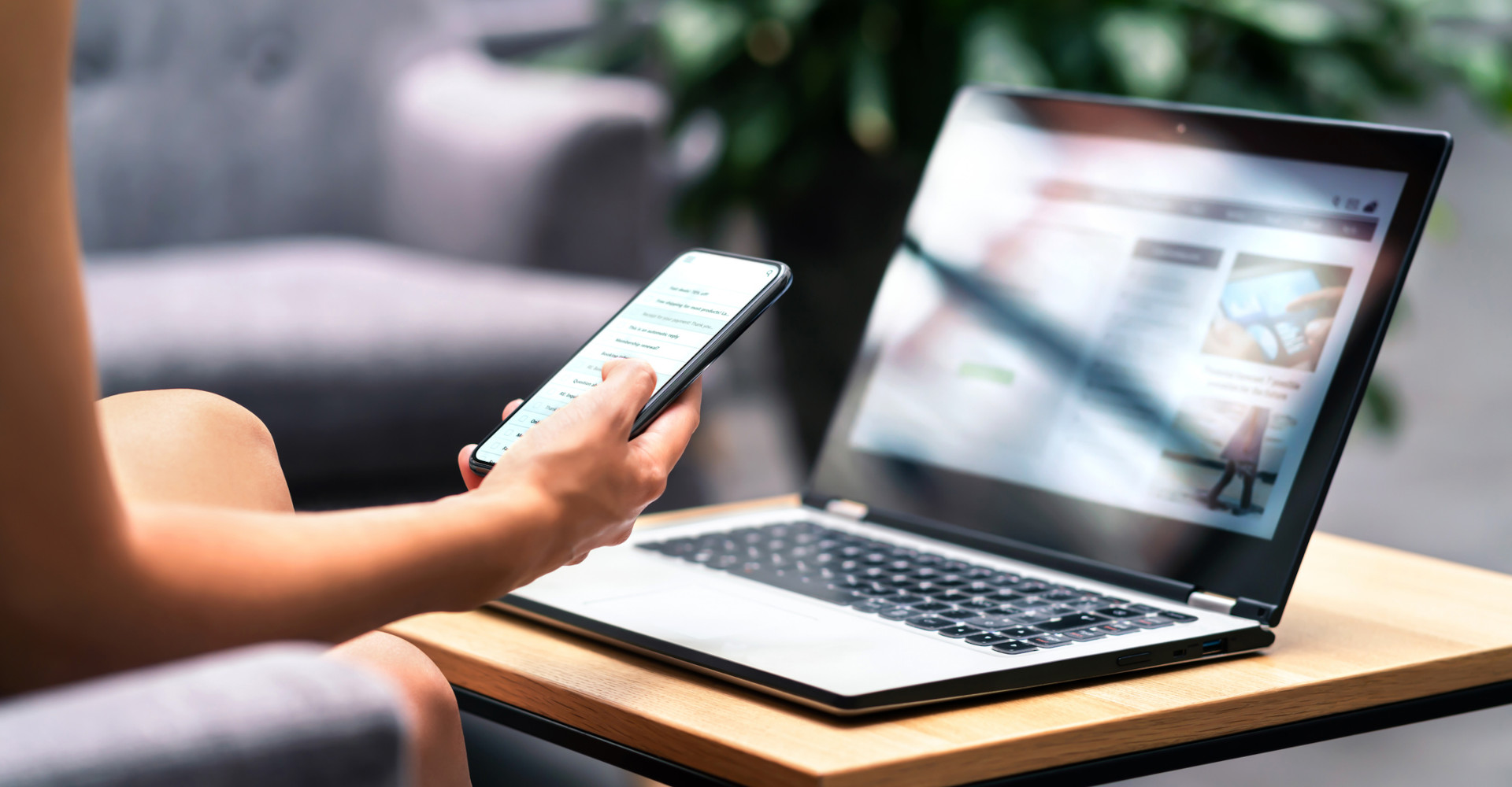 Woman using a laptop and phone to find a website.